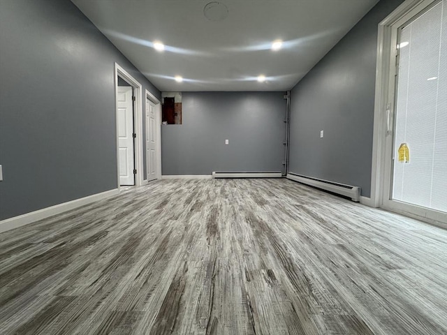 unfurnished room featuring a baseboard heating unit, a baseboard radiator, wood finished floors, and baseboards