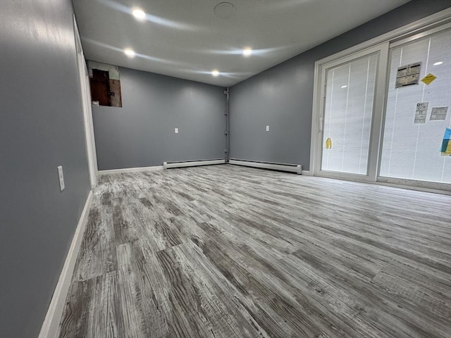 empty room featuring baseboard heating, recessed lighting, wood finished floors, and baseboards