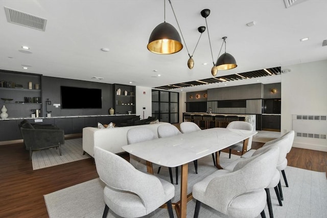 dining room featuring dark hardwood / wood-style floors, built in features, and radiator