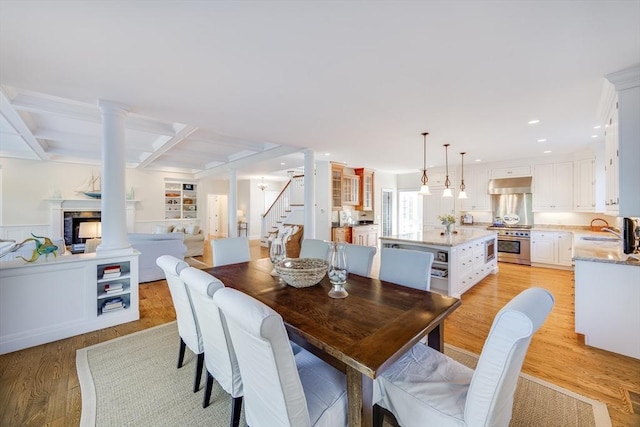 dining room with coffered ceiling, sink, decorative columns, beam ceiling, and light hardwood / wood-style floors