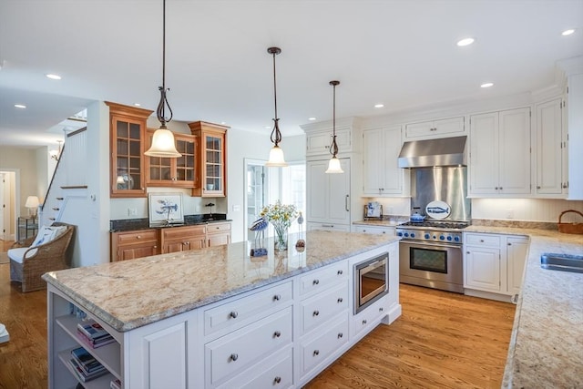 kitchen featuring a kitchen island, appliances with stainless steel finishes, pendant lighting, and range hood