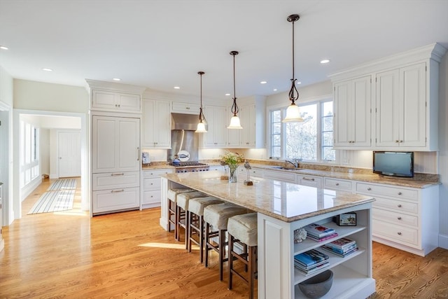 kitchen with a center island, pendant lighting, white cabinets, and a kitchen bar