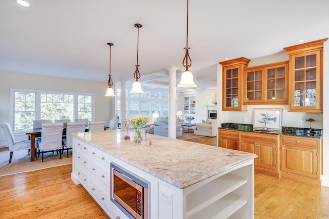 kitchen featuring a kitchen island, pendant lighting, stainless steel microwave, dark stone countertops, and white cabinets