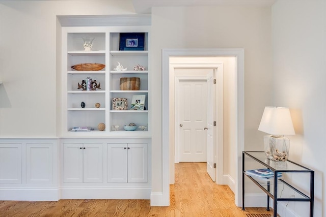 hall with built in features and light hardwood / wood-style floors