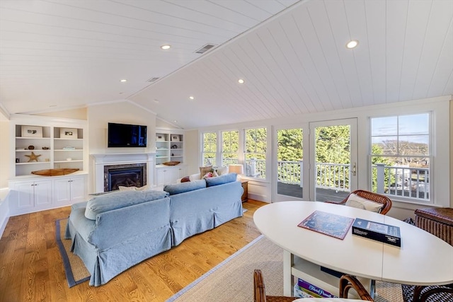 living room with vaulted ceiling, a wealth of natural light, light hardwood / wood-style floors, and built in shelves