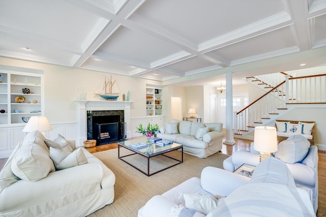 living room featuring built in shelves, a fireplace, coffered ceiling, and light wood-type flooring