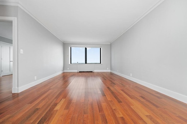 empty room featuring baseboards, wood finished floors, and ornamental molding