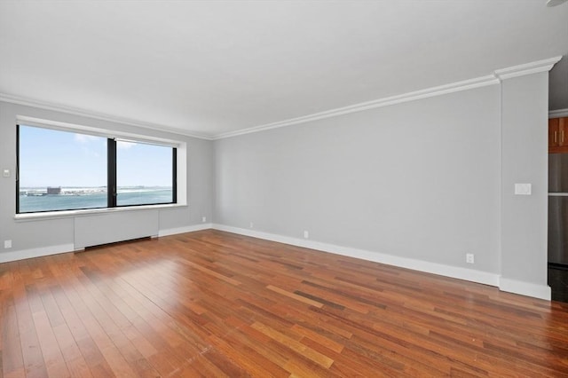 unfurnished room with a water view, crown molding, baseboards, and wood finished floors