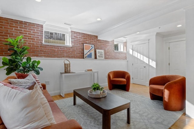 living room featuring crown molding, brick wall, and light hardwood / wood-style floors