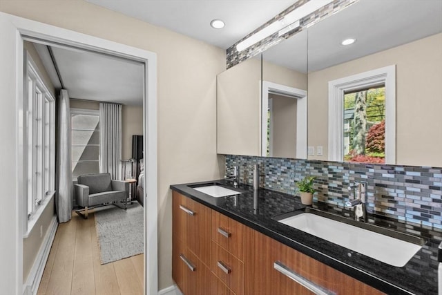 bathroom with decorative backsplash, wood finished floors, double vanity, baseboards, and recessed lighting