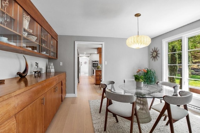 dining area with light wood-type flooring, a chandelier, and baseboards