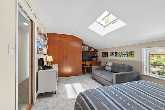 bedroom featuring lofted ceiling, light colored carpet, a skylight, and a desk