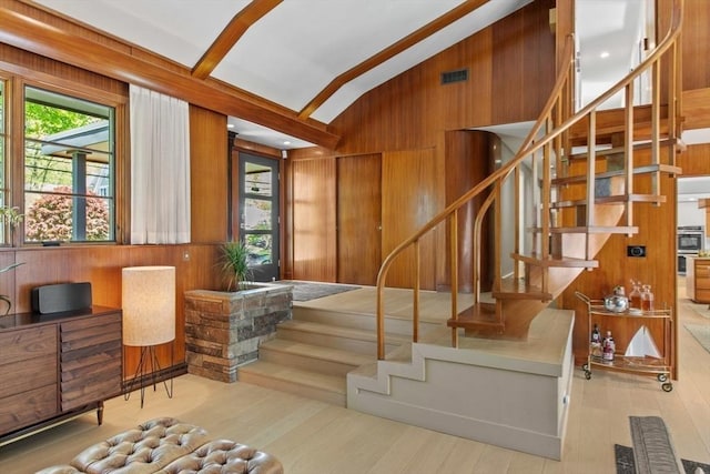 stairway with wood walls, lofted ceiling, and wood finished floors