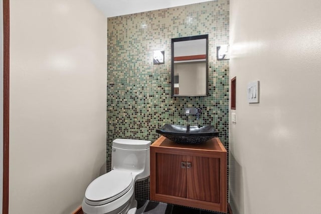 half bathroom featuring tile walls, toilet, and vanity