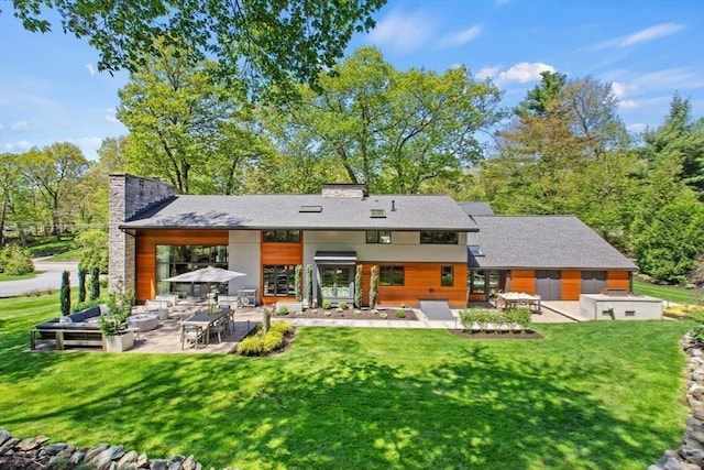 rear view of property with a patio area, a lawn, a chimney, and an outdoor hangout area