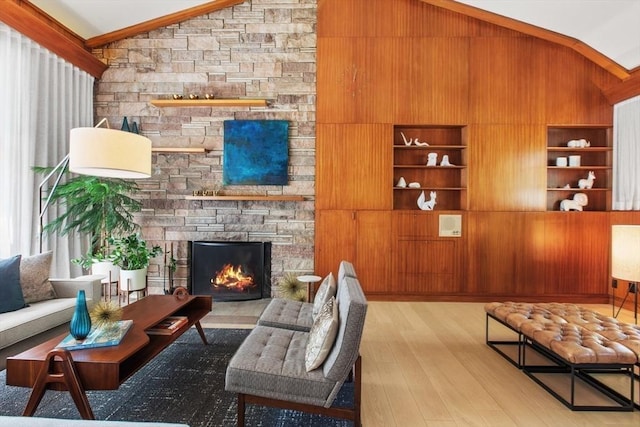 living room with lofted ceiling, wood finished floors, wood walls, a fireplace, and built in features