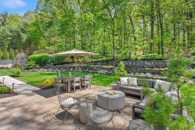 view of patio featuring an outdoor living space with a fire pit, outdoor dining area, and a forest view