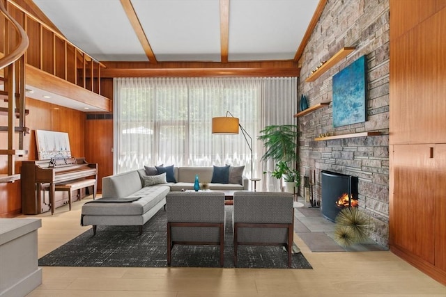 living area featuring a fireplace, wood walls, beamed ceiling, and wood finished floors