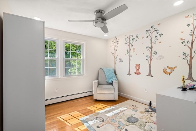 living area featuring a baseboard radiator, wood finished floors, ceiling fan, recessed lighting, and baseboards