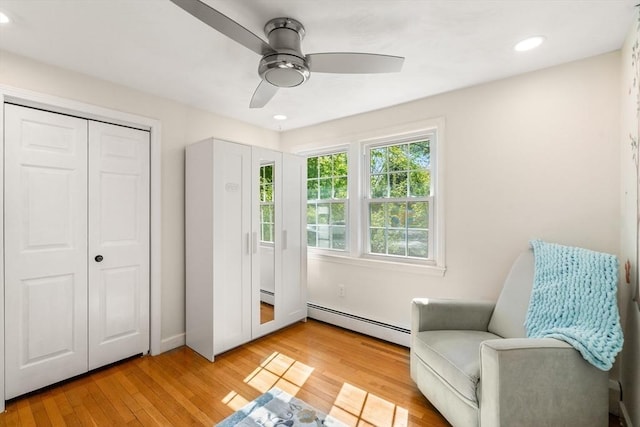living area featuring a baseboard radiator, ceiling fan, recessed lighting, light wood finished floors, and baseboards