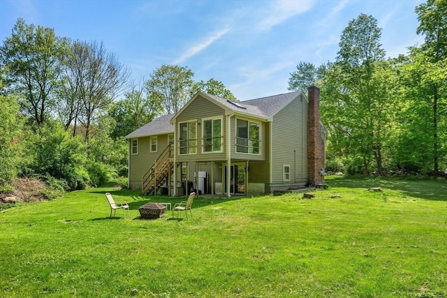 back of property featuring a fire pit, stairs, a yard, and a chimney