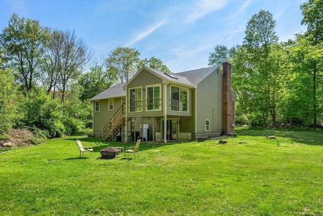 back of property with an outdoor fire pit, stairs, a yard, and a chimney