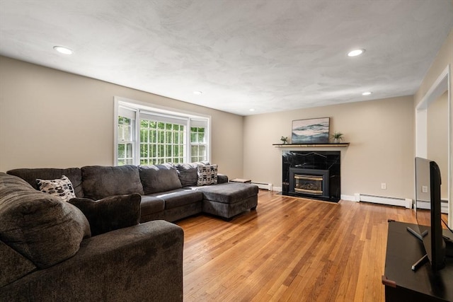 living room featuring a baseboard radiator, light wood-type flooring, recessed lighting, a premium fireplace, and baseboards