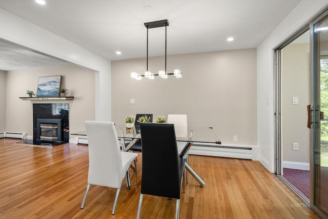 dining space featuring wood finished floors, a baseboard heating unit, a fireplace with flush hearth, recessed lighting, and baseboards