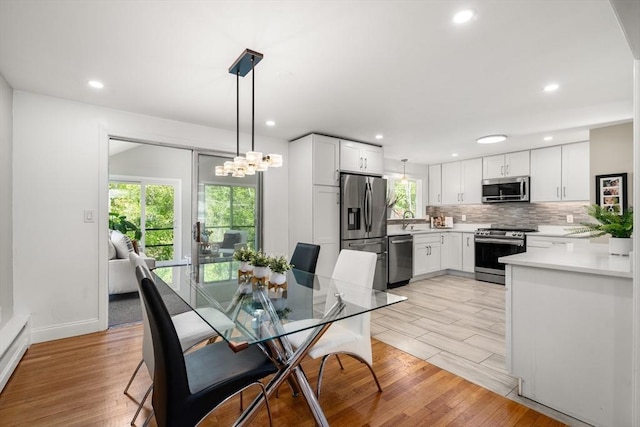 dining room featuring light wood-type flooring, recessed lighting, and baseboards