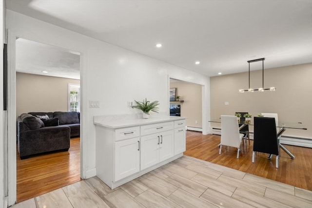 kitchen with white cabinetry, light countertops, hanging light fixtures, light wood-style flooring, and recessed lighting