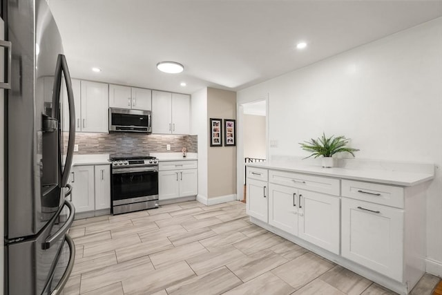 kitchen featuring appliances with stainless steel finishes, backsplash, light countertops, white cabinetry, and recessed lighting