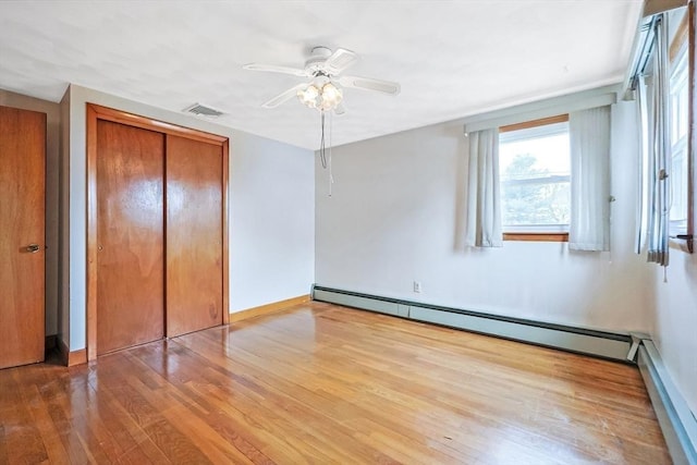 unfurnished bedroom featuring wood finished floors, visible vents, baseboards, a closet, and baseboard heating