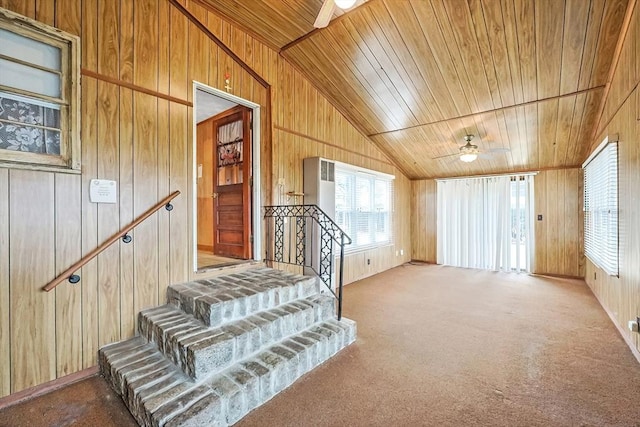 stairway with wooden ceiling, a ceiling fan, wood walls, and carpet floors