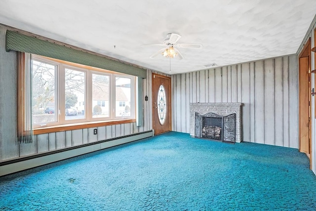 unfurnished living room with a baseboard heating unit, carpet flooring, a fireplace, and a ceiling fan