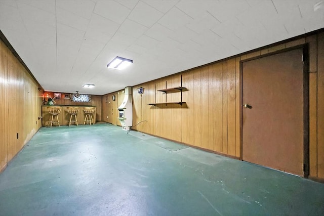 finished basement featuring a bar and wood walls