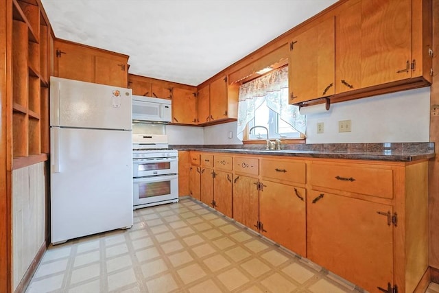 kitchen featuring white appliances, light floors, and dark countertops