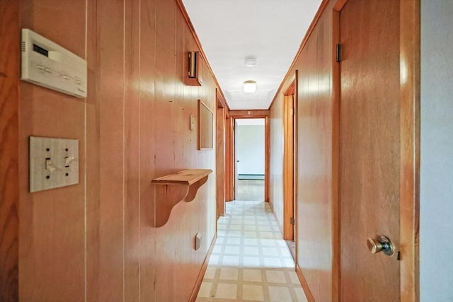 hall with wooden walls, light floors, and baseboard heating