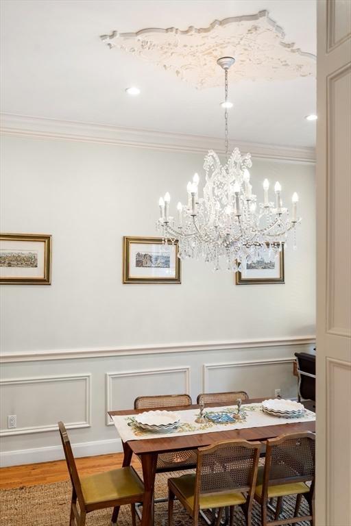 341 Beacon Unit 2F, Boston, MA 02116 - dining area featuring crown molding, wood finished floors, a chandelier, and a decorative wall