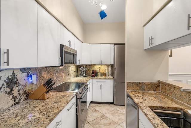 341 Beacon Unit 2F, Boston, MA 02116 - kitchen featuring appliances with stainless steel finishes, tasteful backsplash, white cabinets, light stone counters, and light tile patterned flooring