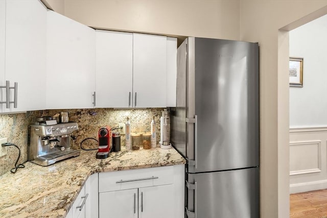 341 Beacon Unit 2F, Boston, MA 02116 - kitchen featuring freestanding refrigerator, decorative backsplash, white cabinetry, light stone counters, and wood finished floors