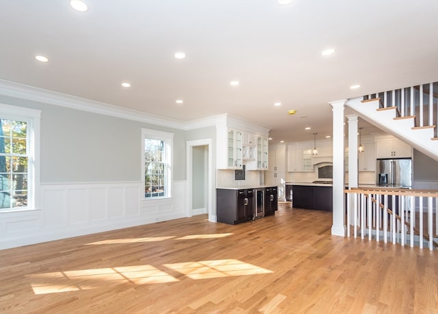 unfurnished living room with decorative columns, light hardwood / wood-style flooring, and crown molding