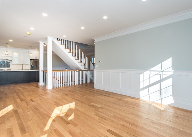 unfurnished living room with light hardwood / wood-style flooring, ornamental molding, and ornate columns