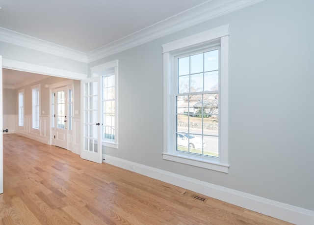 doorway featuring french doors, light wood-type flooring, crown molding, and a healthy amount of sunlight