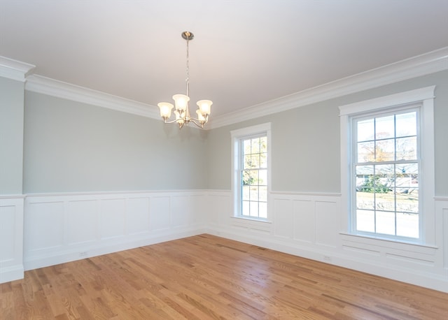 spare room with ornamental molding, a notable chandelier, hardwood / wood-style flooring, and plenty of natural light