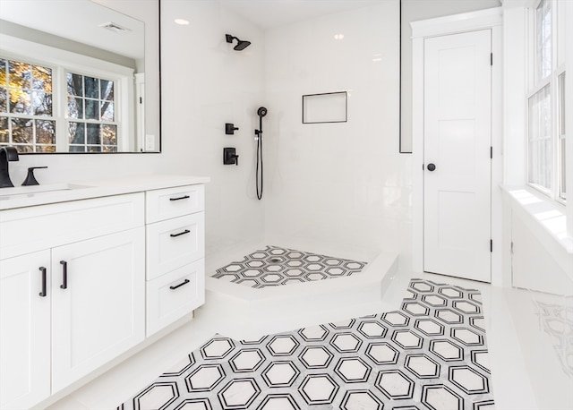 bathroom with a tile shower, tile patterned flooring, and vanity