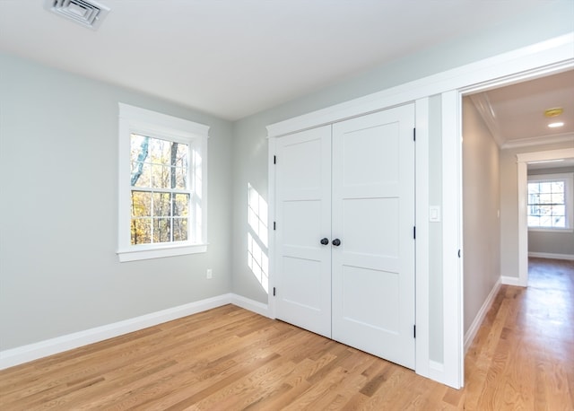 unfurnished bedroom featuring light hardwood / wood-style floors, a closet, and crown molding