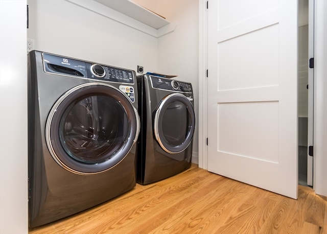 laundry area with washing machine and dryer and light hardwood / wood-style flooring