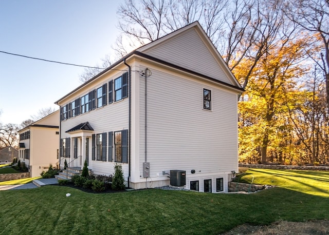 view of property exterior with central AC and a lawn