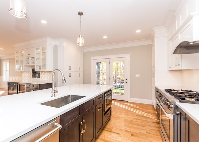 kitchen with white cabinetry, sink, hanging light fixtures, light hardwood / wood-style flooring, and appliances with stainless steel finishes