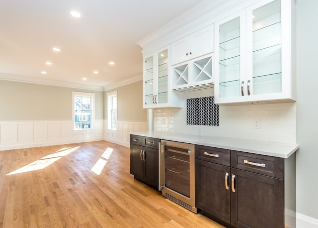 kitchen featuring decorative backsplash, light wood-type flooring, dark brown cabinetry, white cabinets, and wine cooler